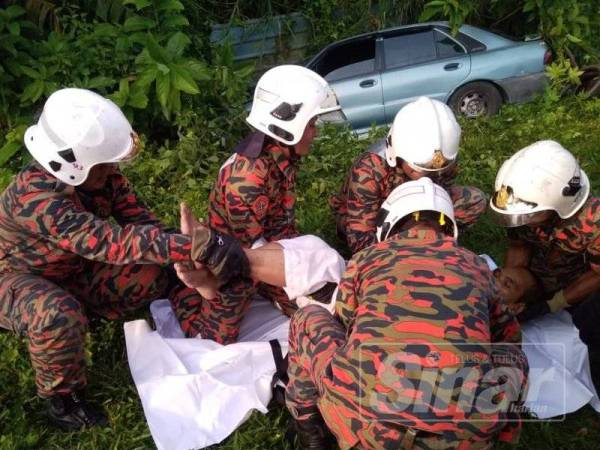 Anggota BBP Sungai Siput bertungkus lumus mengeluarkan mayat mangsa tersepit di dalam kenderaan.