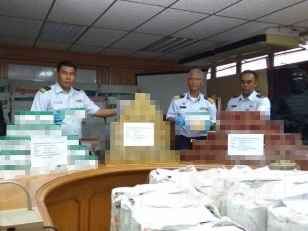 Wan Mat (tengah) menunjukkan rokok seludup yang berjaya dirampas pasukannya ketika rondaan Op Pagar Laut berhampiran muara Sungai Bernam Hutan Melintang awal pagi tadi.