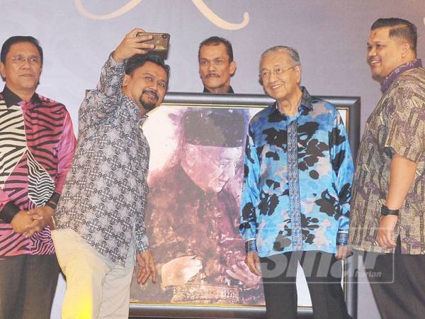 Perdana Menteri Malaysia, Tun Dr. Mahathir Mohamad sempat berswa foto ketika acara lelongan pada majlis Makan Malam, Malam Sejuta Kenangan yang diadakan di Setia City Convention Centre. - FOTO SINAR HARIAN/ROSLI TALIB