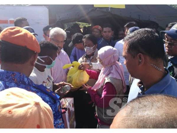 Dr Wan Azizah (tengah) menyerahkan bantuan makanan kepada orang asli di sini.