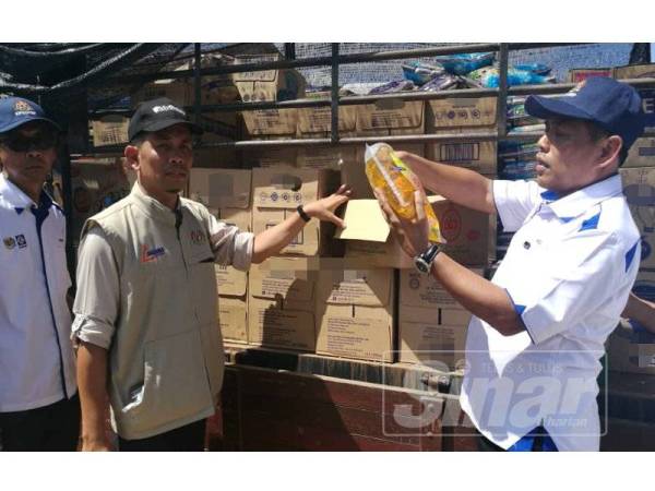 Muez (kanan) menunjukkan sebahagian bantuan makanan dan keperluan harian untuk manfaat orang asli di perkampungan orang asli Kuala Koh hari ini.