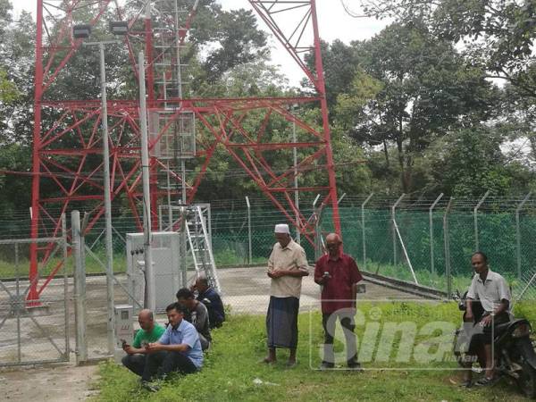 Rozali (tiga dari kanan) bersama Hashim (dua dari kanan) dan penduduk berkumpul di kawasan pencawang telekomunikasi untuk dapatkan talian telefon.