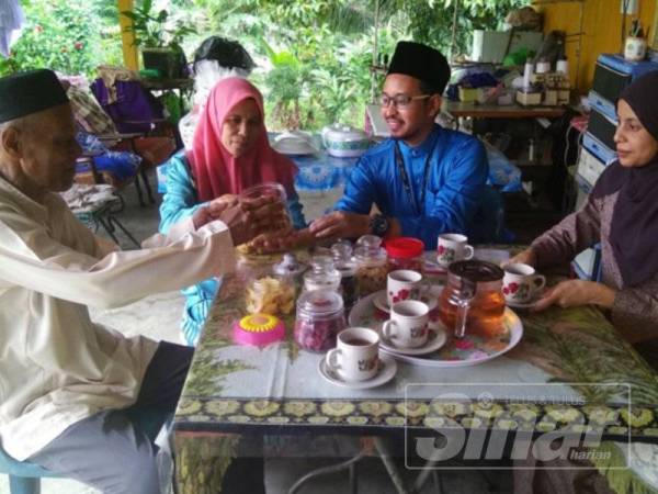 Buges bersama Timah (dua dari kanan) menjamu Sharifah Huda (kanan) dan Harith (dua dari kanan) dengan kuih raya di rumahnya di Kampung Tengah Batang Melaka kelmarin.