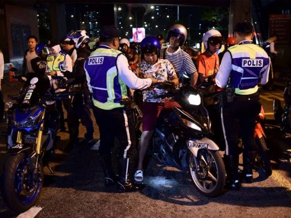 Anggota Polis dari Jabatan Siasatan dan Penguatkuasaan Trafik (JSPT) Kuala Lumpur melakukan pemeriksaan ke atas sebahagian motosikal yang ditahan pada Operasi Motosikal dan Pelbagai Kesalahan Lalulintas di Jalan Bangsar menghala pusat bandar malam tadi. - FOTO BERNAMA