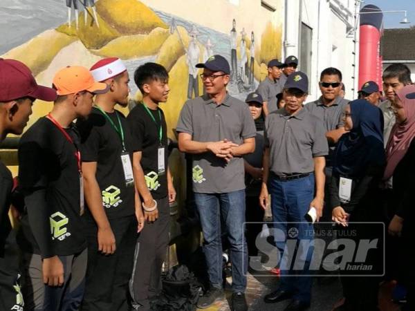 Kar Hing (lima dari kiri), berkata sesuatu kepada kumpulan pelajar yang terlibat dalam proses menyiapkan mural di Lorong Hill.