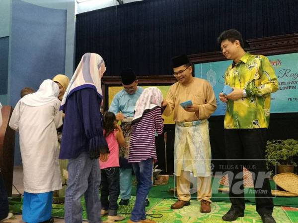 Akmal (dua,kanan) menyampaikan duit raya kepada kanak-kanak yang menghadiri Majlis Sambutan Hari Raya dan Rumah Terbuka Parlimen Johor Bahru di sini, hari ini.