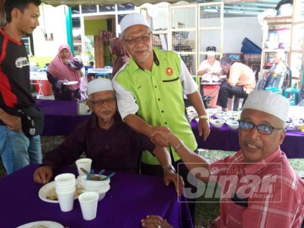 Abd Nasir berdiri bersalam dengan mantan JKKK Becah Sawah, Fuad Othman dalam majlis Aidilfitri hari ini.