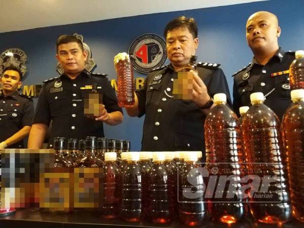 Che Zaimani (dua, kanan) menunjukkan botol arak dipercayai tiruan yang dirampas dari sebuah premis.