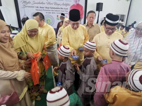 Salahudin (tengah) dan Mohd Anuar (dua, kanan) ketika menyampaikan sumbangan duit raya kepada anak-anak yatim sempena Majlis Hari Raya Aidifitri Lestary Heights hari ini.