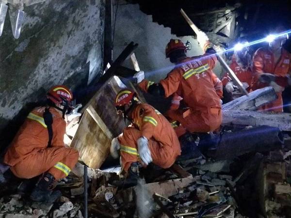 Pasukan bomba bertungkus-lumus mengeluarkan mangsa yang terperangkap di bawah runtuhan bangunan. 