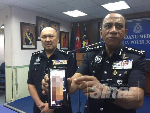 Ketua Polis Johor, Datuk Mohd Khalil Kader Mohd menunjukkan minuman keras yang disyaki mengandungi bahan kimia beracun.