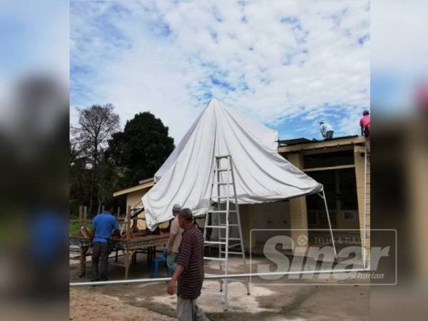 Penduduk bergotong-royong menurunkan kanopi dari atas bumbung Masjid Al Solehin, Kubang Bemban pagi semalam.