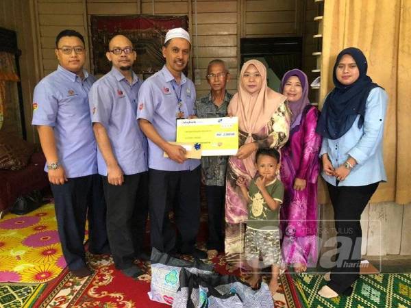 Wan Izani (tiga dari kiri) bersama rombongan yang menyampaikan bayaran RM2,000 kepada Norlizma di rumah mereka di Kampung Aman Lundang tadi.
