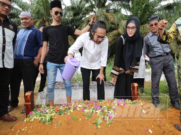 Mawi menyiram air mawar ke atas pusara ibunya.