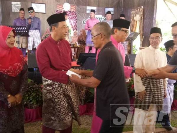 Mohamad Yasid (dua dari kiri) mengiringi Abdul Rashid (dua dari kanan) menyerahkan sumbangan duit raya kepada penerima pada Majlis Mesra Aidilfitri MPK di Taman Pengkalan Batu, hari ini.