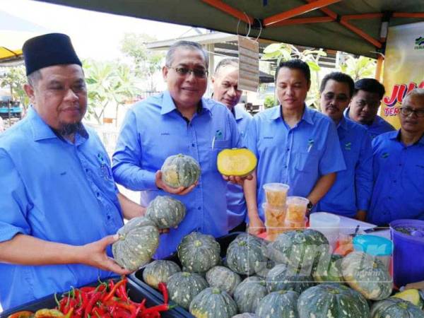 Zainal Abidin (dua dari kiri) dan Fauzi (kiri) menunjukkan labu manis yang turut dijual di Agrobazaar Fama Chendering.