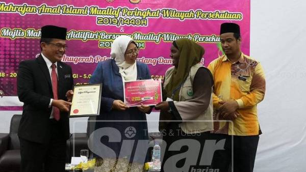 Fuziah (dua dari kiri) menyampaikan sijil penghargaan kepada pemenang program Mahrajan Amal Islami Mualaf Peringkat Wilayah Persekutuan Tahun 2019 di Kompleks Darul Hidayah, Kuala Lumpur semalam, sambil disaksikan Mohd Ajib (kiri).