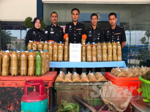 Mohd Marzukhi (tengah) menunjukkan air dan daun ketum yang berjaya dirampas daripada dua lelaki sekitar Chenderong Balai di sini hari ini. 