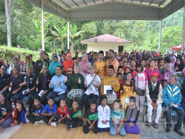 Boon Chye (duduk, tengah) bersama warga SK Pos Raya dan penduduk kampung bergambar bersama-sama pada majlis tersebut, di sini hari ini.