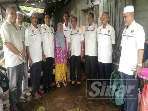 Yusof (tiga dari kanan) hadir menyerahkan bantuan keperluan asas kepada Rosminah di rumah di Kampung Hilir, di sini semalam.