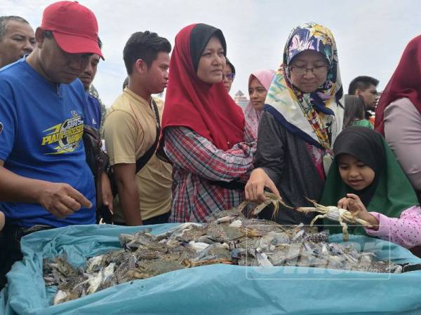 Orang ramai memilih ketam pada harga murah yang dijual di Pulau Warisan, hari ini.