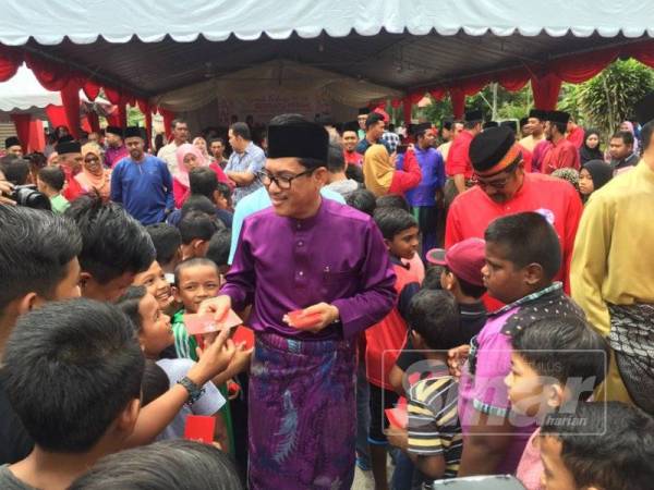 Ahmad Faizal menyampaikan duit raya kepada kanak-kanak yang hadir pada majlis sambutan hari raya, di sini hari ini.