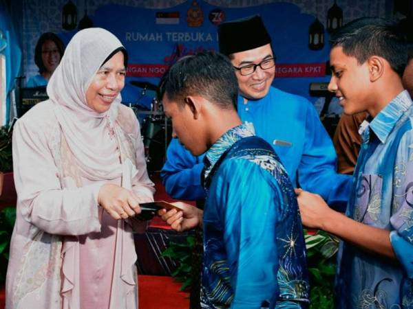 Zuraida Kamaruddin (kiri) menyampaikan sumbangan duit raya kepada golongan anak yatim pada Majlis Rumah Terbuka Perdana Aidilfitri Anjuran Gabungan NGO Penggerak Dasar Komuniti Negara KPKT di Balai Bomba dan Penyelamat Jasin Bestari, hari ini. - FOTO BERNAMA