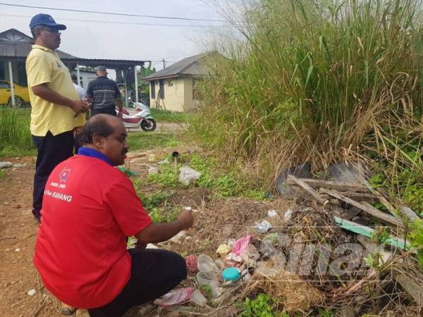 Vidyananthan (kanan) melihat longgokan sampah yang dikhuatiri menjadi tempat pembiakan nyamuk aedes di Taman Sri Lambak, Kluang semalam. 