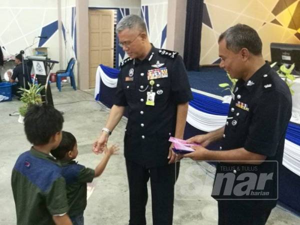 Hasanuddin (kiri) turut menyampaikan sumbangan duit raya, bersama Suzaimi (kanan) dalam majlis sambutan Aidilfitri di IPD Tanah Merah di sini hari ini.