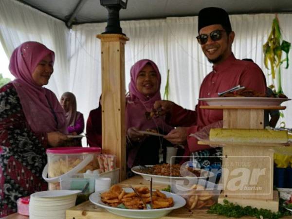 Hasnul Zulkarnain (kanan), di sebuah geri makanan pada majlis jamuan Aidilfitri berkenaan.