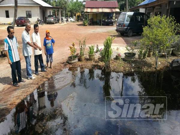 Dari kanan, Kami, Sahak dan Isnin (kanan) menunjukkan keadaan air parit yang sering melimpah ketika hujan lebat di Kampung Parit Yasin, Benut. 