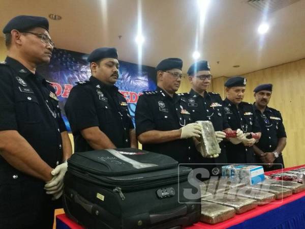 Mohd Fahmi (tiga, kiri) menunjukkan rampasan yang dibuat susulan tertangkapnya seorang lelaki di Kampung Baru, Kuala Lumpur, Khamis lalu.