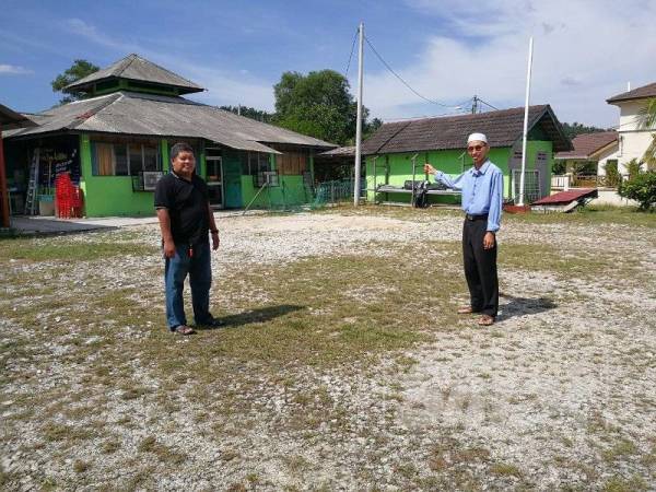 Zamri (kanan) bersama Zulhelmi menunjukkan tapak surau sementara yang mahu dibangunkan bangunan baharu di Alam Suria. 