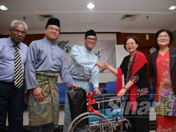 Ahmad Faizal menyempurnakan simbolik penyerahan kerusi roda kepada Pengarah HRPB, Dr Teo Gim Sian.