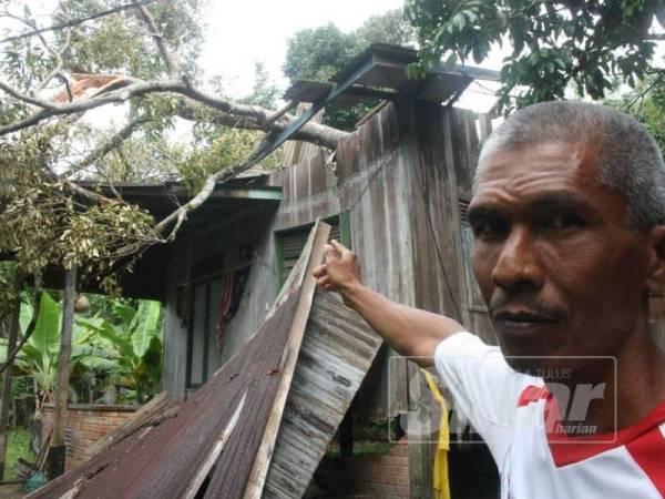 Nor Azman menunjukkan rumahnya yang rosak akibat ditimpa pokok durian dalam kejadian ribut semalam.