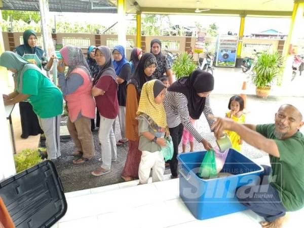 Seorang ajk masjid sedang mengedarkan beras cupak kepada keluarga yang berdaftar.