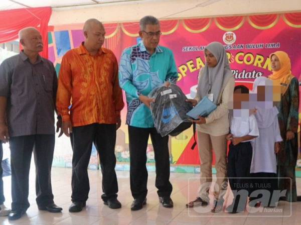 Ismail (tiga dari kiri) menyampaikan sumbangan beg sekolah kepada Norhayani di SK Buloh Lima,di sini hari ini.