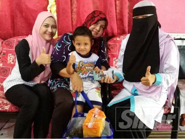 Maznah (kanan) menyerahkan sumbangan wang tunai dan barangan makanan kepada Faridah (dua dari kiri) sambil diperhati Annas Mikhail (tengah) di rumahnya di Kampung Tanah Kebun, Parit Buntar hari ini.