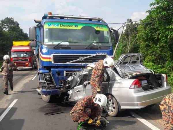 Anggota bomba ketika cuba mengeluarkan mangsa daripada kenderaannya, di sini semalam.