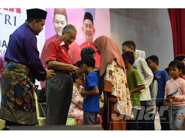 Mahathir menyampaikan sumbangan duit raya kepada kanak-kanak yang hadir di majlis berkenaan, di sini hari ini.