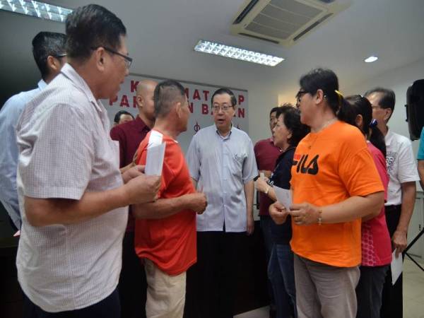 Menteri Kewangan Lim Guan Eng beramah mesra dengan penerima bantuan bencana ribut pada 22 Jun di Pusat Khidmat DAP Bagan hari ini. - Foto Bernama