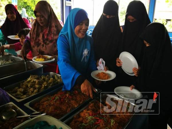 Norhayati (tengah) melayan tetamu yang hadir pada majlis sambutan Aidilfitri Wanita PKR Cabang Marang.