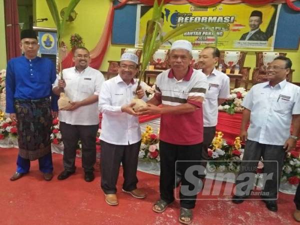 Phahrolrazi (tiga dari kiri) menyampaikan anak pokok kepada penerima selepas merasmikan Program Reformasi Peladang Rantau Panjang di Sekolah Menengah Kebangsaan Agama (SMKA) Lati.