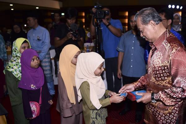 Muhyiddin menyampaikan sumbangan duit raya kepada sebahagian 40 anak yatim dan golongan asnaf dari perumahan Flat Sri Sarawak dan Flat San Peng pada Program Kelestarian Pertubuhan Pendaftar anjuran Jabatan Pendaftar Pertubuhan Malaysia (JPPM) hari ini. -Foto Bernama