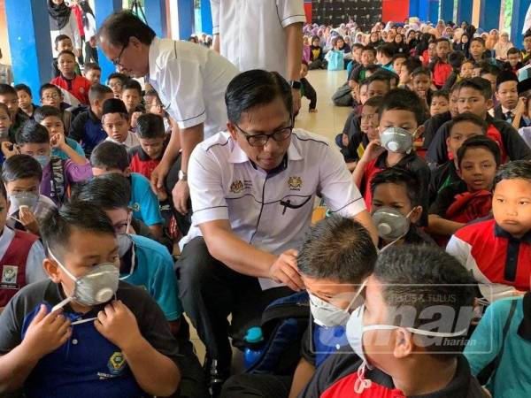 Azman membetulkan penutup mulut dan hidup salah seorang murid SK Pasir Gudang 4.