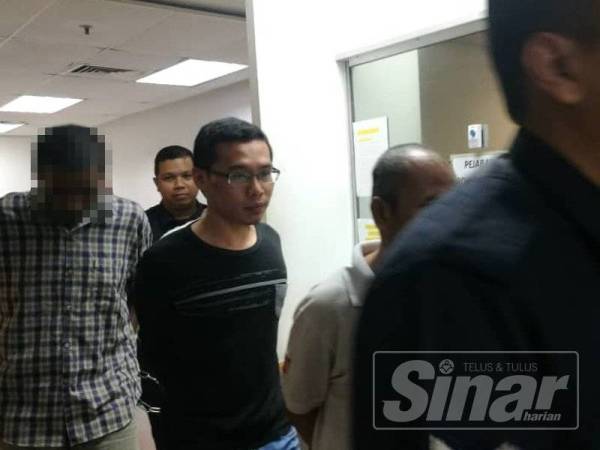 Luqman Hakim (berbaju T hitam) diiringi polis mahkamah selepas selesai prosiding, hari ini.