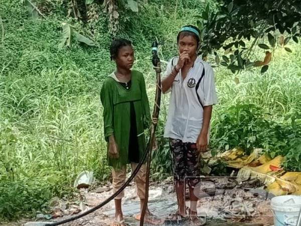 Kanak-kanak orang asli Kampung Kuala Koh menggunakan air bukit yang disediakan untuk mandi.