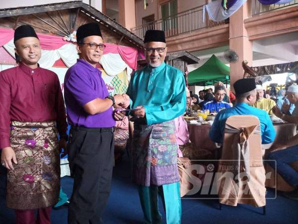 Ibrahim Bakri (kanan) menyampaikan hadiah kepada wakil Hospital Machang yang dinobatkan johan pertandingan gerai tercantik pada Majlis Sambutan Aidilfitri Peringkat Jajahan Machang.