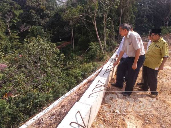 Chee Wan (Kiri) dan Rozilani meninjau tembok terbabit dari permandangan atas rumah Robiah