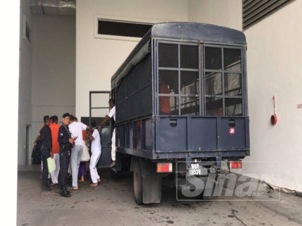 Ketiga-tiga tertuduh berbaju putih dibawa keluar dari trak polis setibanya di pekarangan Mahkamah Tinggi, Muar.